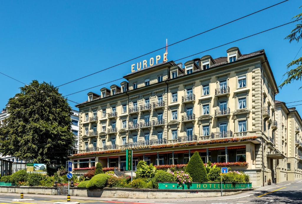 un grand bâtiment avec un panneau en haut dans l'établissement Grand Hotel Europe, à Lucerne