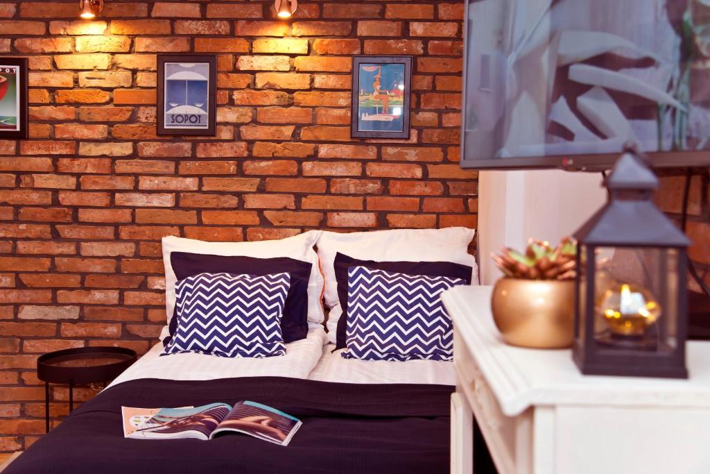a bed in a room with a brick wall at Pomorskie Apartamenty Biała Mewa in Sopot