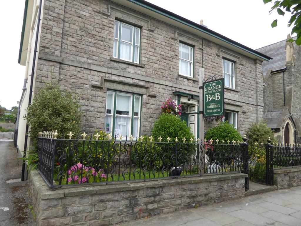 a brick house with a fence in front of it at The Grange Guest House in Brecon