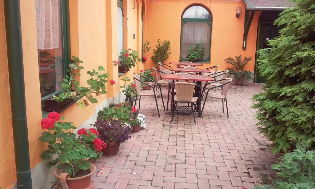 un patio al aire libre con mesas, sillas y flores en Piros Ponty Panzió, en Poroszló