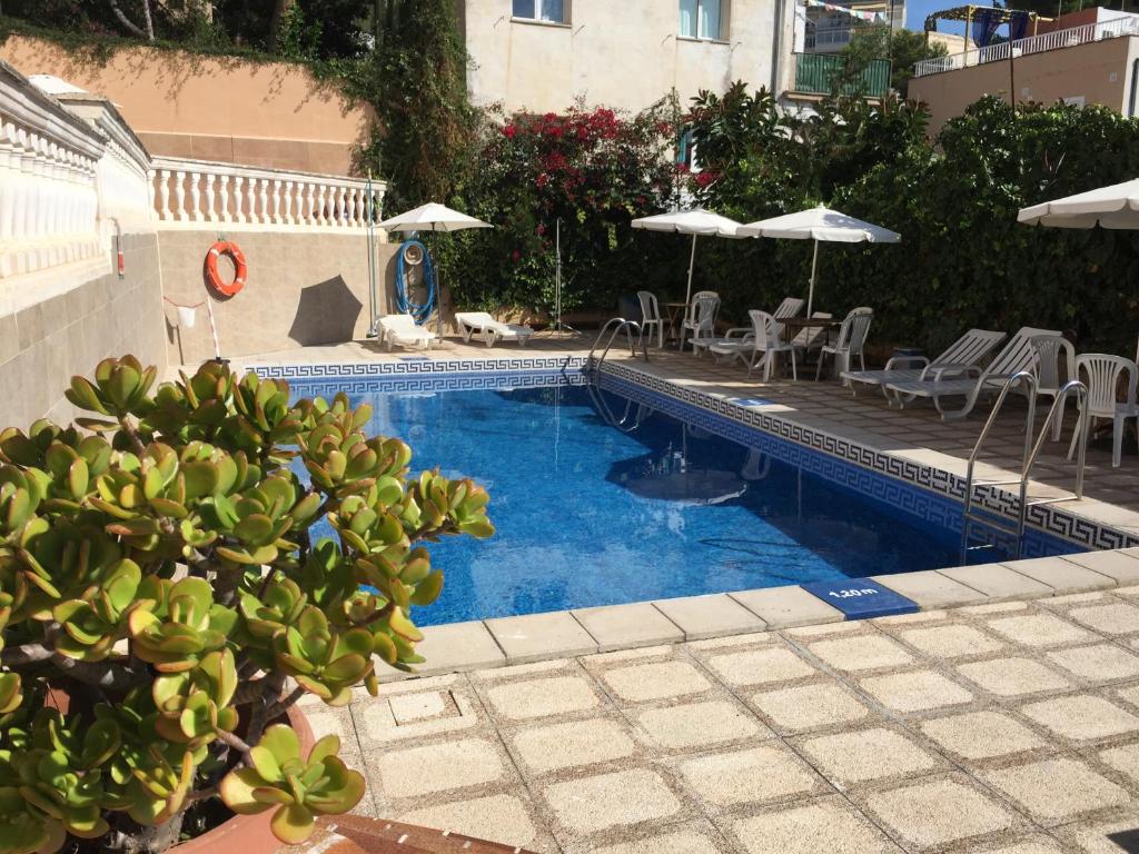 a swimming pool with tables and chairs and umbrellas at Hostal San Telmo in Palma de Mallorca