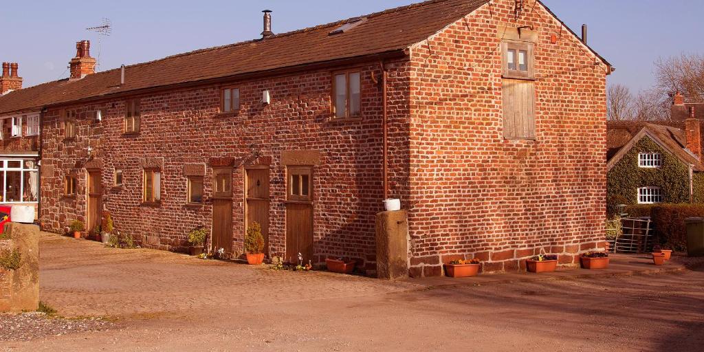 ein altes Backsteingebäude mit Topfpflanzen davor in der Unterkunft The Old Mill Barn with Hot Tub and Private Pool in Wirral