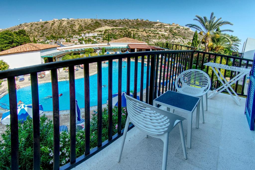 a balcony with chairs and a view of a pool at Hylatio Tourist Village in Pissouri