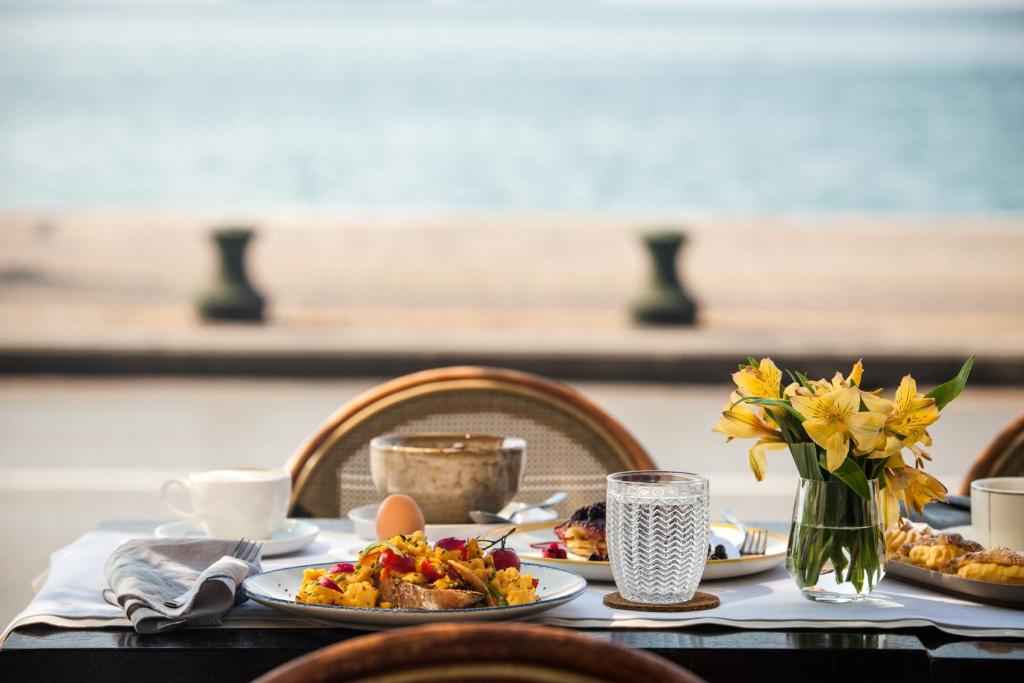 a table with plates of food and a vase of flowers at Daios Luxury Living in Thessaloniki