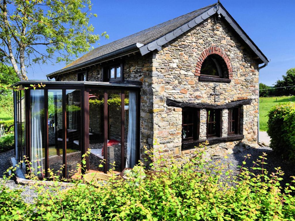 uma extensão a uma casa de pedra com portas de vidro em Romantic holiday house in the Ardennes with garden and view em Nadrin