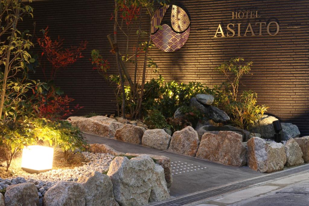 大阪的住宿－Tabist Hotel Asiato Namba，一座花园,在一座建筑前有岩石和植物