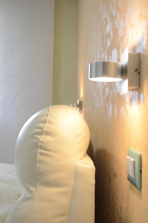 einen weißen Stuhl in einem Schlafzimmer mit einem Licht an der Wand in der Unterkunft Casa Aurora B&B in Chieti
