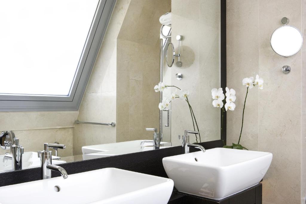 a bathroom with two white sinks and a mirror at Daios Luxury Living in Thessaloniki