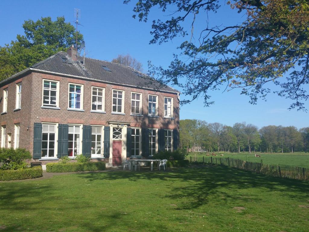 un gran edificio de ladrillo con un patio de césped en Hotel Restaurant Roerdinkhof, en Winterswijk