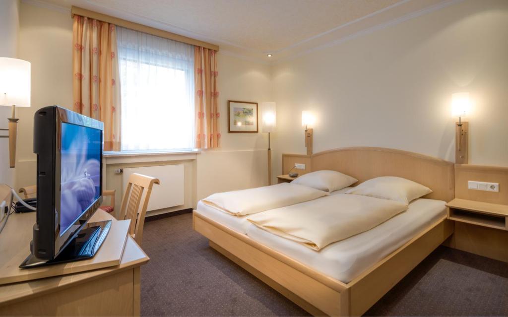 a bedroom with a bed and a television on a desk at Hotel Gasthof zur Post in Munich