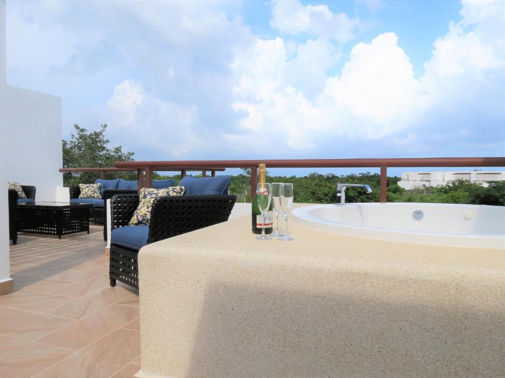 a balcony with a tub and a table and chairs at Bahia Principe, TAO, Luxury Penthouse in Akumal