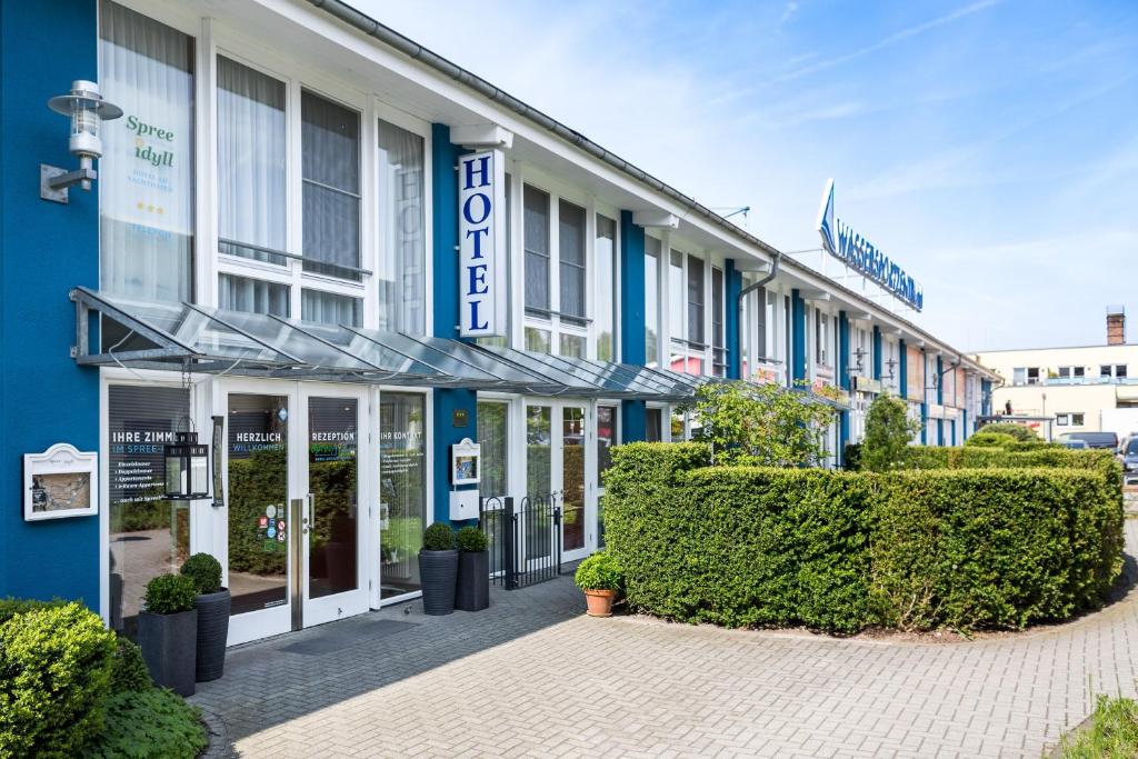 un edificio azul y blanco con arbustos delante de él en Hotel Spree-idyll en Berlín