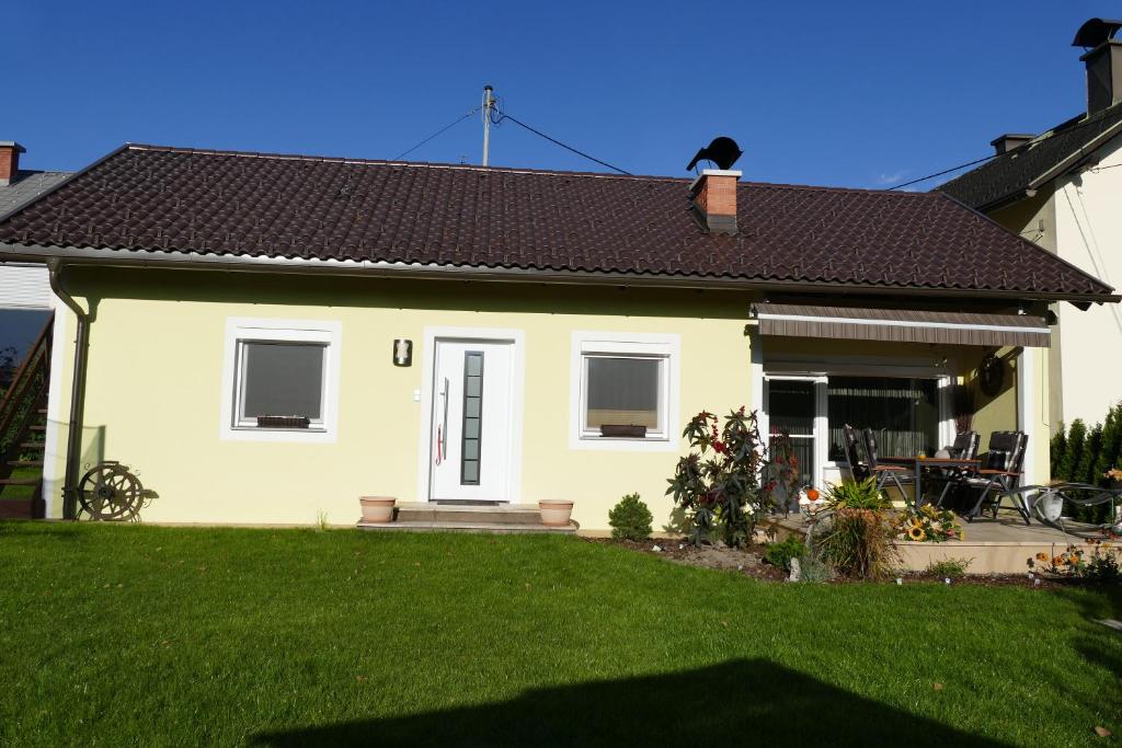 ein kleines gelbes Haus mit einem Rasenplatz in der Unterkunft Ferienwohnung Stichauner in Bodensdorf