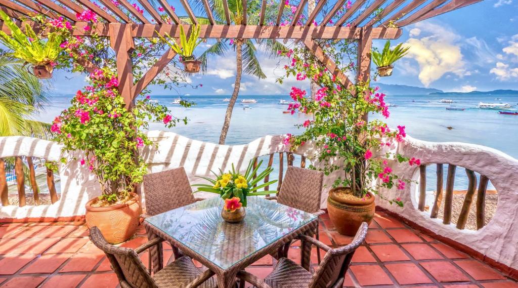 einen Tisch und Stühle auf einer Terrasse mit Blumen in der Unterkunft Atlantis Dive Resort Puerto Galera in Puerto Galera