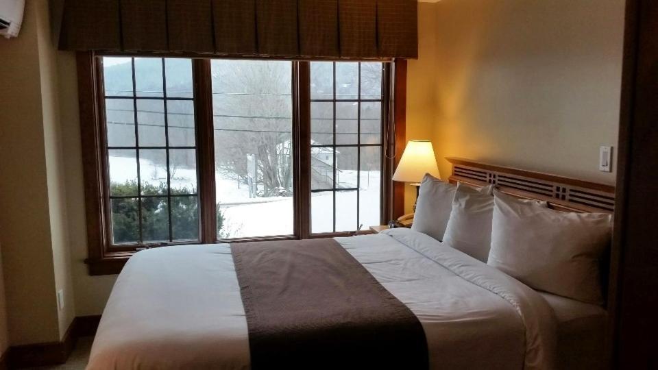 a bedroom with a large bed and a large window at Winwood Inn & Condominiums in Windham