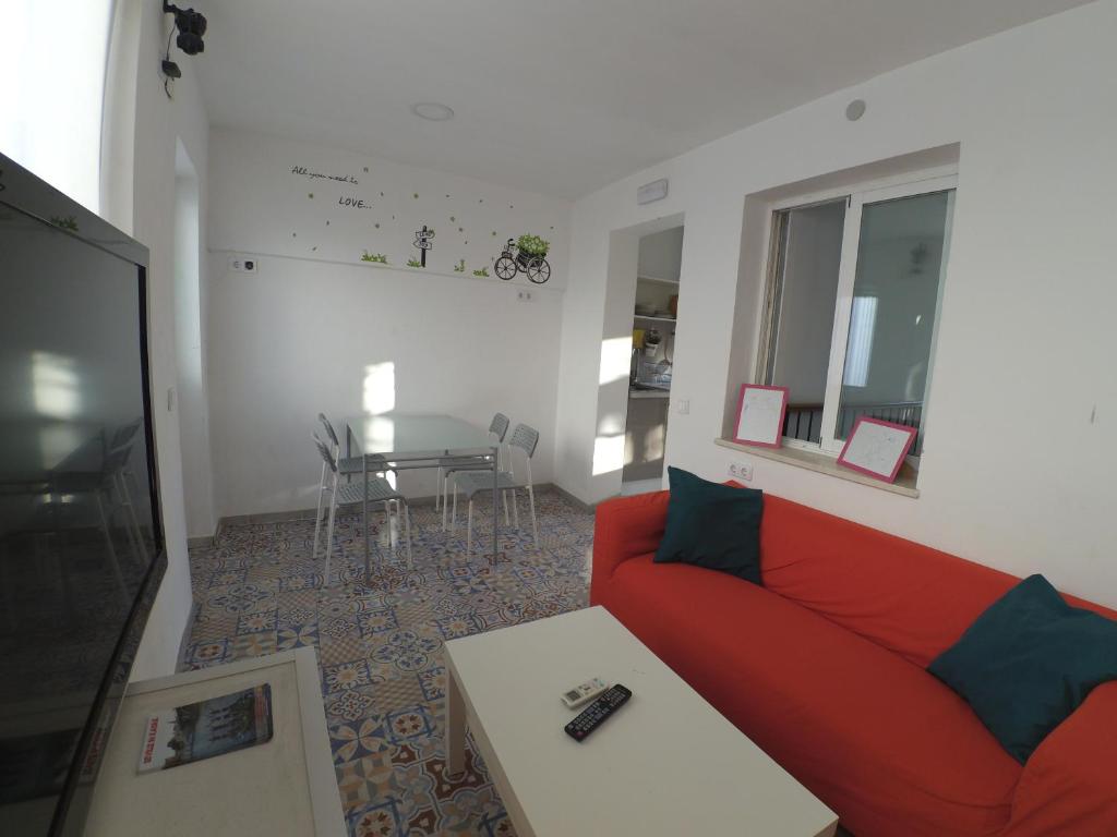 sala de estar con sofá rojo y mesa en The Spot Central Hostel, en Sevilla