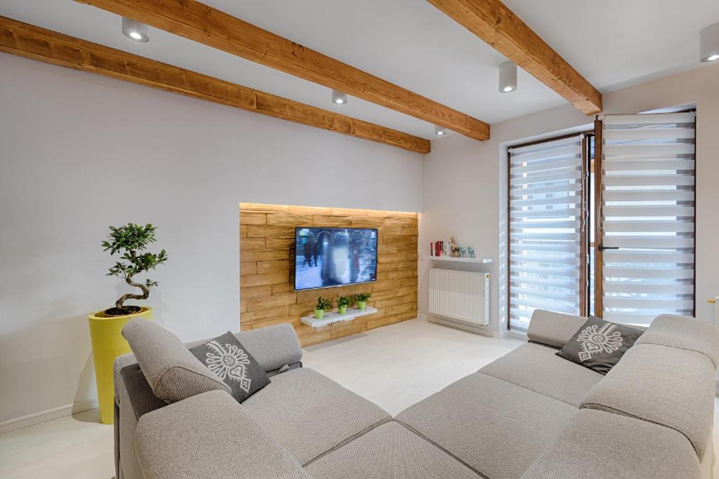 uma sala de estar com um sofá e uma televisão de ecrã plano em Apartamenty Gubałówka em Zakopane