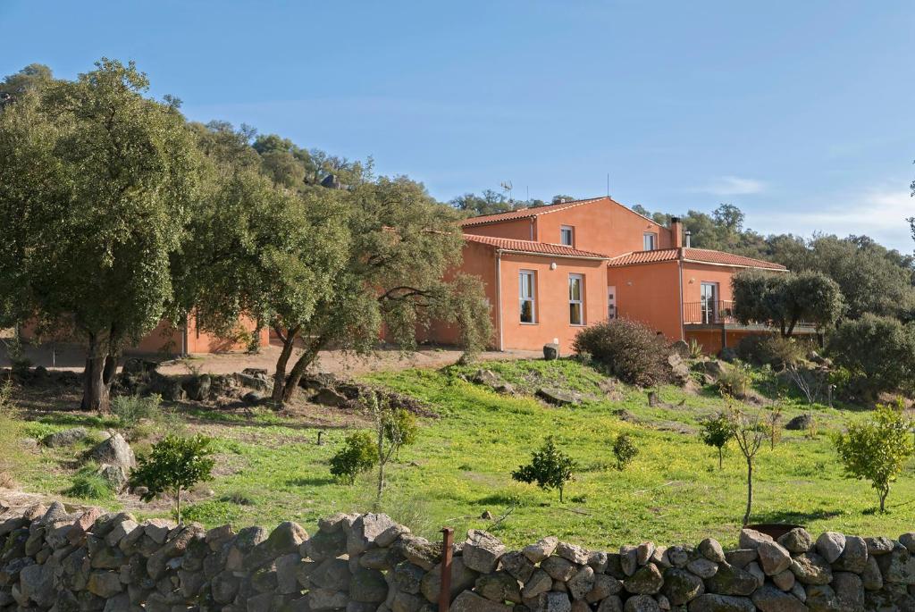a house on a hill next to a stone wall at Finca el Rabilargo in Arroyomolinos de Montánchez