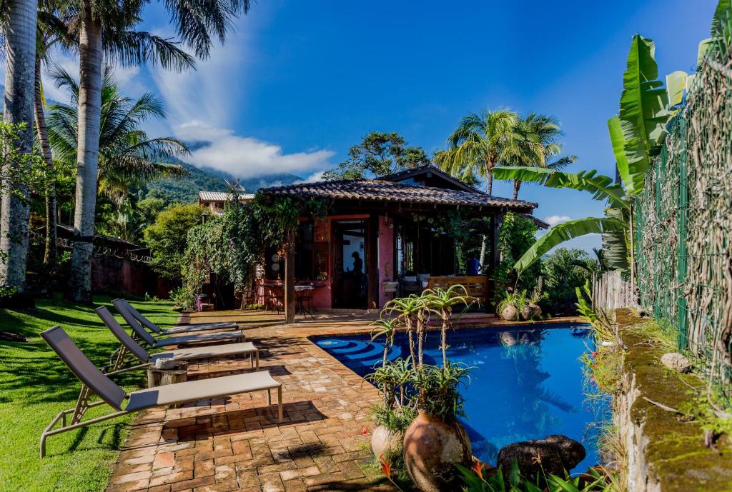 a house with a swimming pool and a resort at Feiticeira Guesthouse in Ilhabela