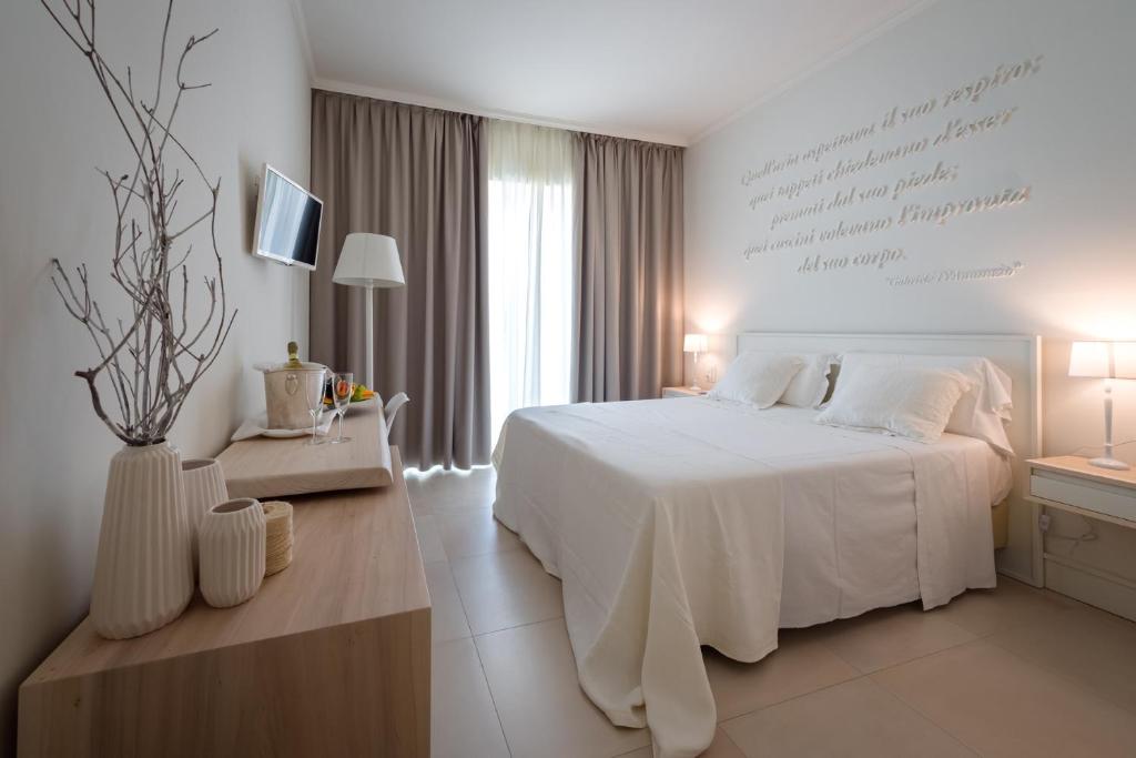 a white bedroom with a white bed and a window at La Chiave dei Trabocchi in San Vito Chietino