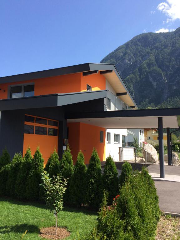 a house with an orange facade with mountains in the background at Appartement Schusternagele in Amlach