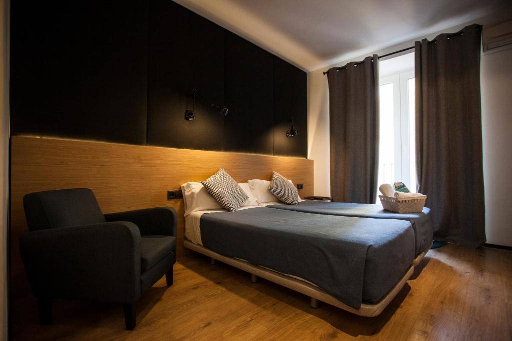 um quarto com uma cama, uma cadeira e uma janela em CC Malasaña em Madri