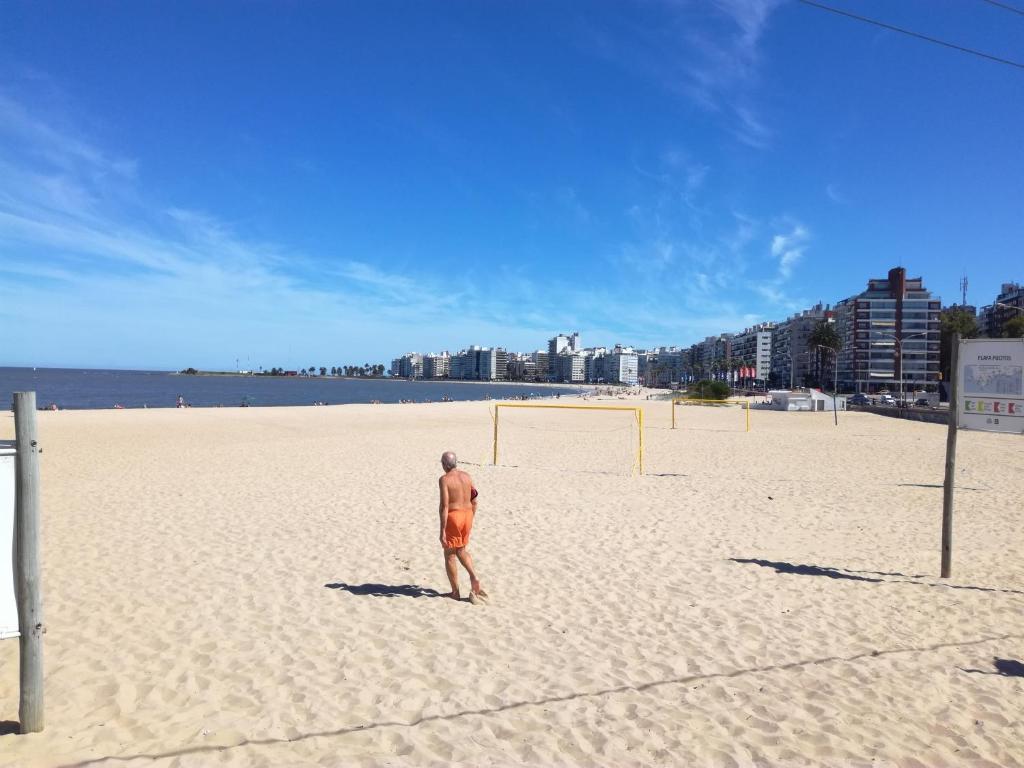 um homem de pé numa praia com uma bola de futebol em Stone Wasi em Montevidéu