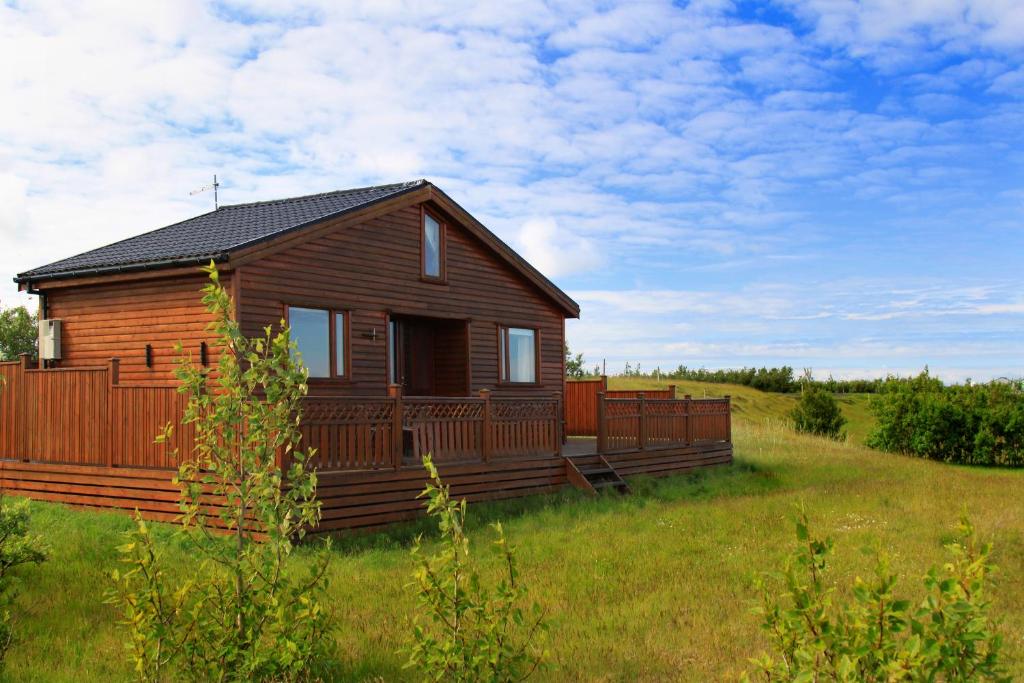 una cabaña de madera en un campo con un campo verde en Cozy Cottage by Stay Iceland, en Hvolsvöllur