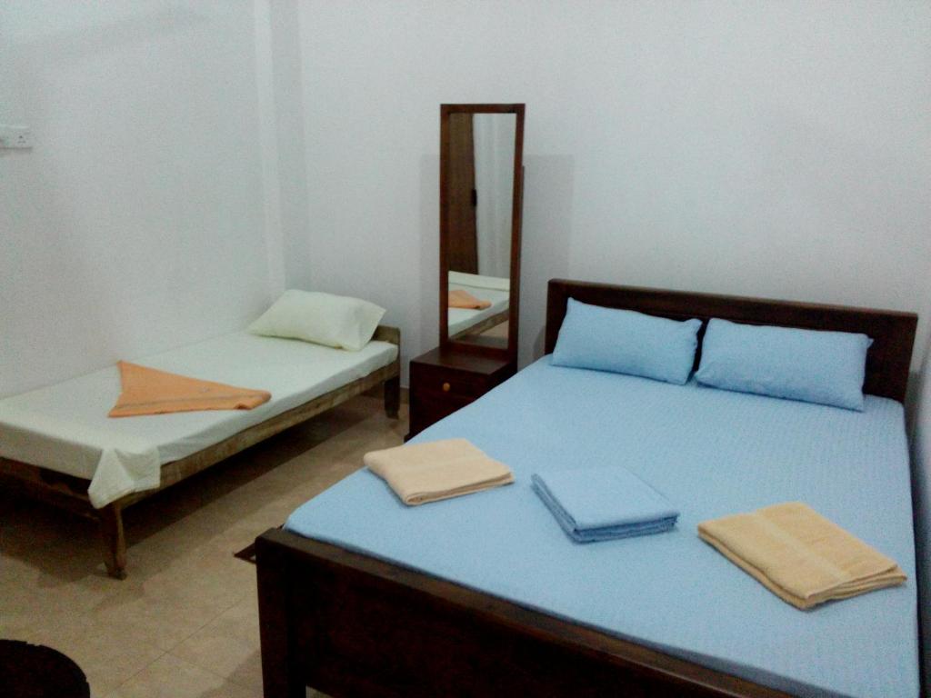 1 dormitorio con 2 camas y espejo en Diyawara Home Stay, en Anuradhapura