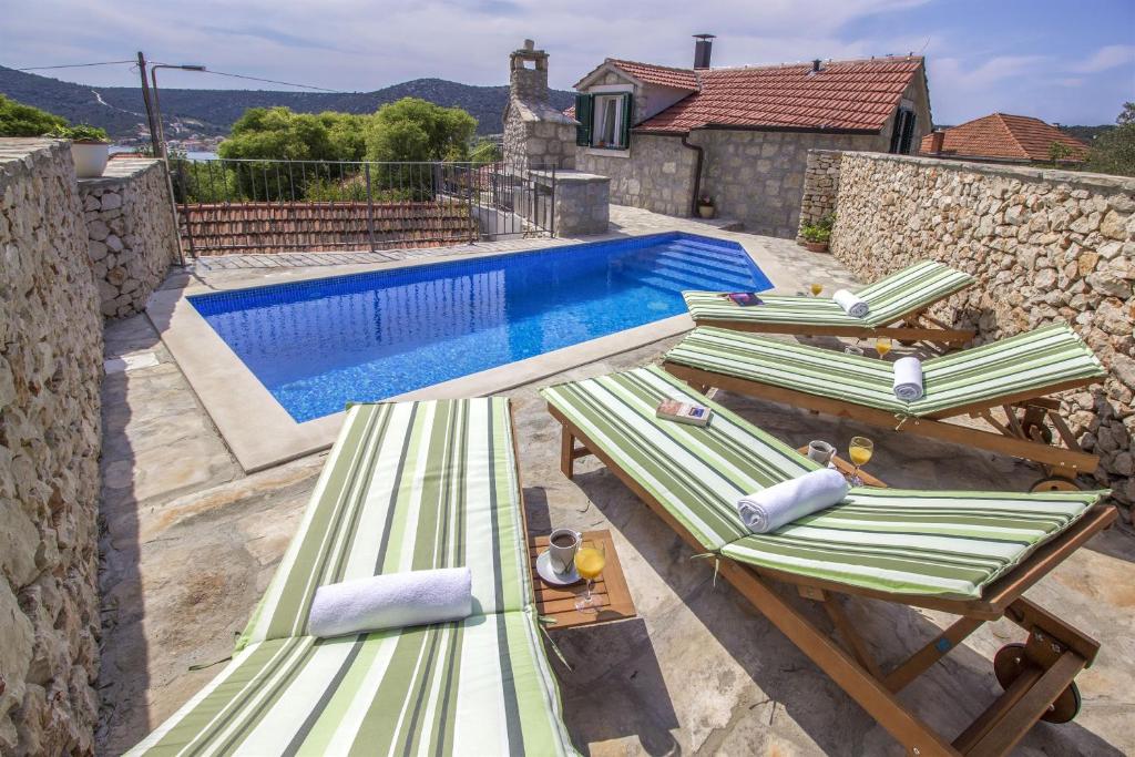 a group of lounge chairs next to a swimming pool at Dalmatian stone Villa Burica in Vinišće