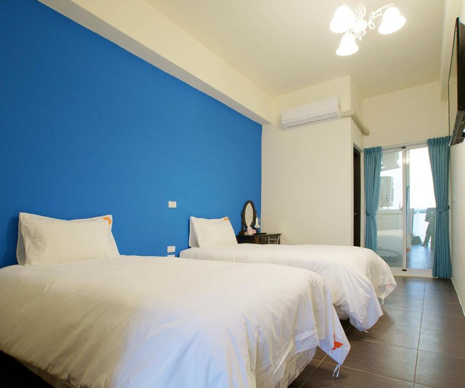 - 2 lits dans une chambre avec un mur bleu dans l'établissement Trip Village-Hulk's Homestay, à Taïtung
