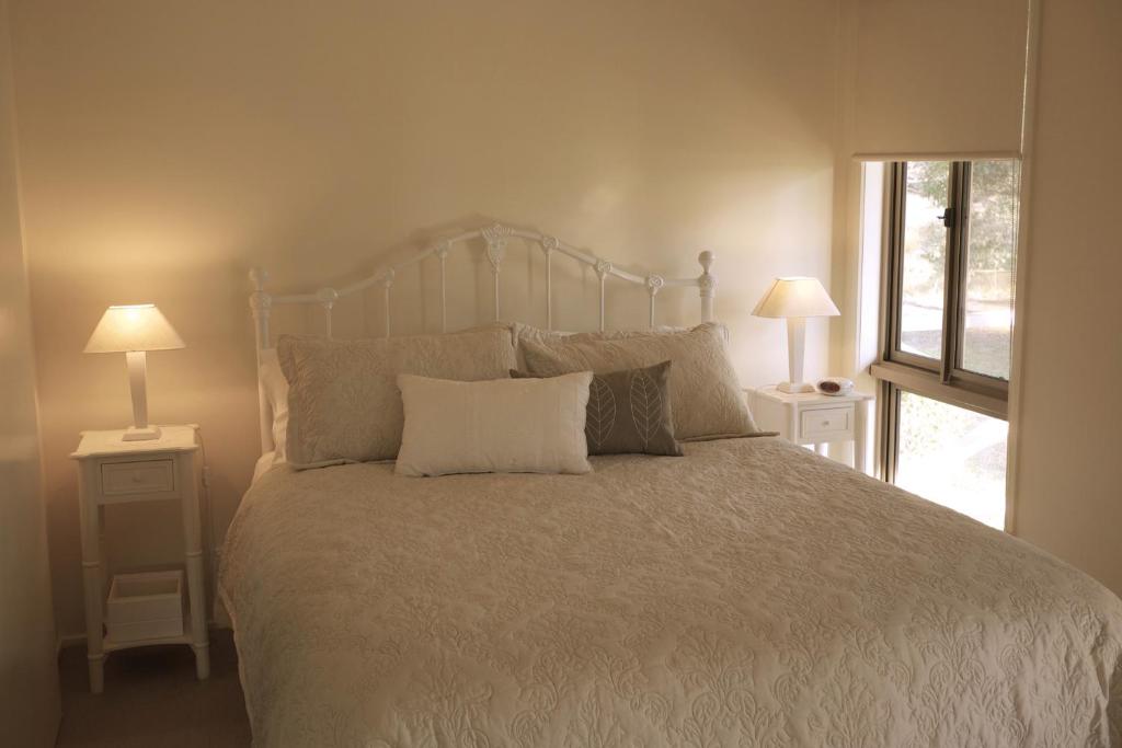 NyoraにあるLittle Lake Cottageのベッドルーム1室(大型ベッド1台、ナイトスタンド2台付)