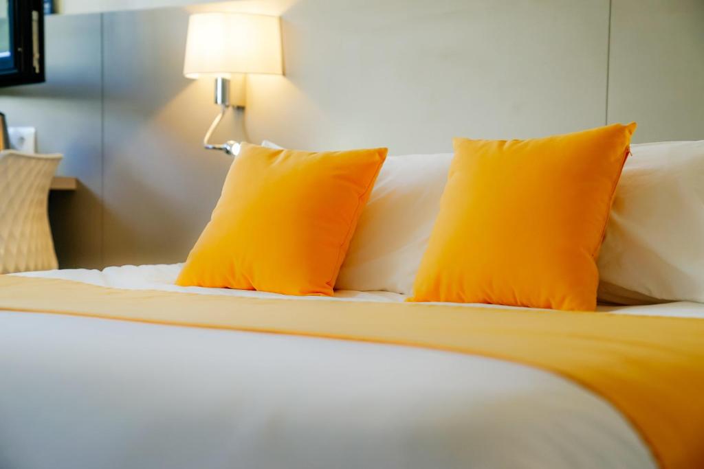 uma cama com duas almofadas laranjas em cima em Kyriad Lille - Roncq em Roncq