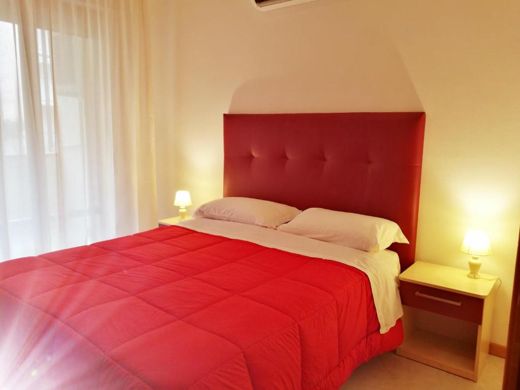 un letto rosso in una camera da letto con due lampade di Aparthotel Costa Paradiso a Lido Adriano