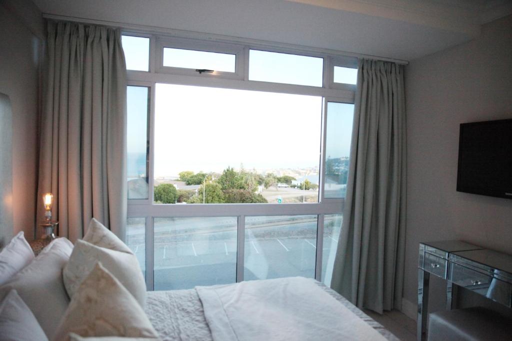 a bedroom with a bed and a large window at view at the bay 4 in Mossel Bay