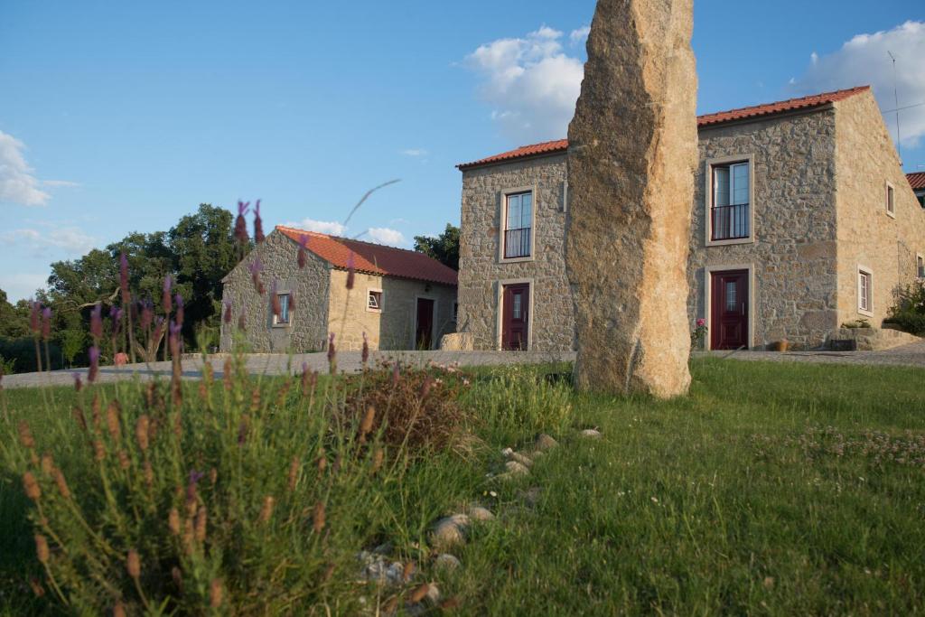 uma velha casa de pedra num campo com uma árvore em Quinta da Pedra Grande em Monsanto