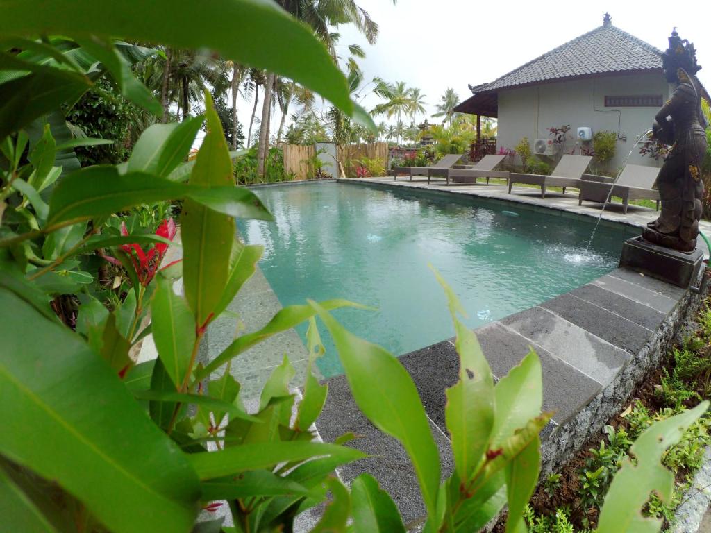 una piscina con una estatua frente a una casa en Amaya Cottage Ubud by Svaha Hospitality, en Ubud