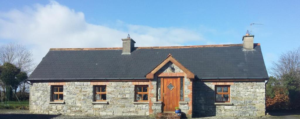 uma pequena casa de pedra com um telhado preto em Hazel Cottage em Limerick