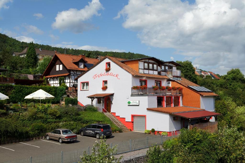 un bâtiment avec des voitures garées dans un parking dans l'établissement Gasthaus Trifelsblick, à Wernersberg