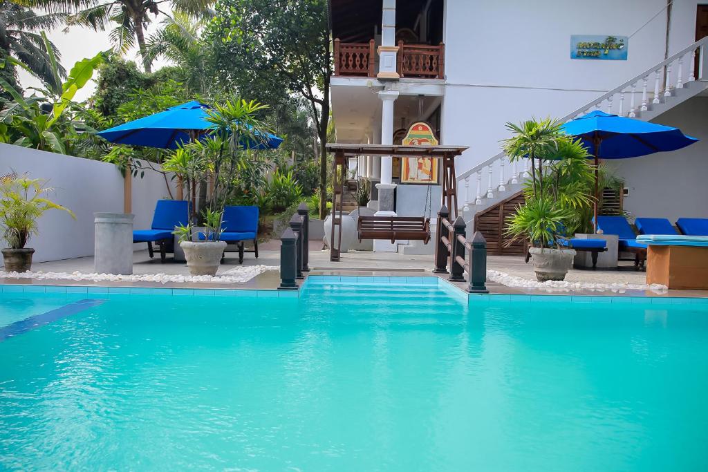 ein Pool in einem Hotel mit blauen Stühlen und Sonnenschirmen in der Unterkunft Morning Star in Mirissa