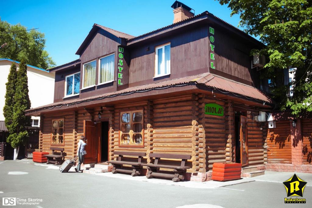 a man walking in front of a wooden house at Hostel Hola in Chernihiv