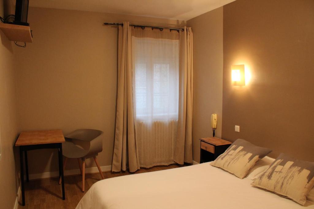 Schlafzimmer mit einem Bett, einem Schreibtisch und einem Fenster in der Unterkunft Les Glycines in Remoulins