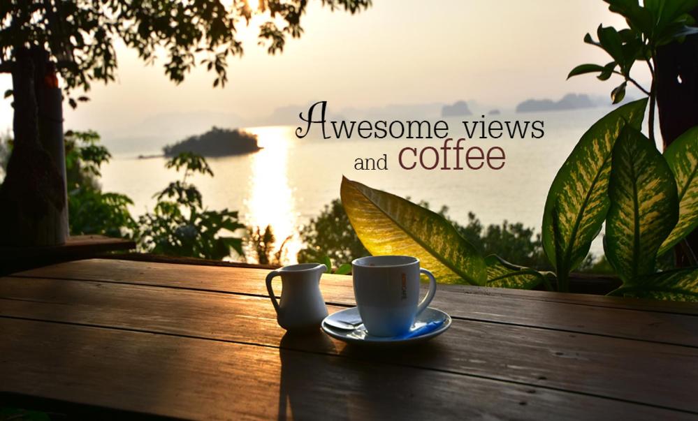 a cup of coffee on a wooden table with a view of the water at Tha Khao Bay View in Ko Yao Noi