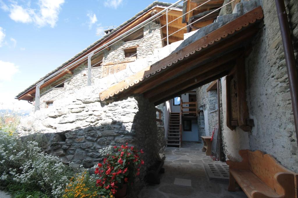 a stone building with a wooden awning and flowers at Appartamenti Peroulaz in Charvensod