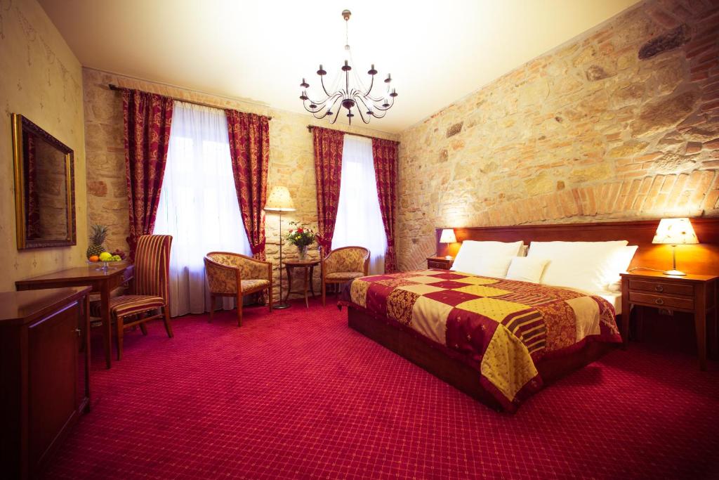 a hotel room with a bed and a table and chairs at Hotel Rous in Plzeň