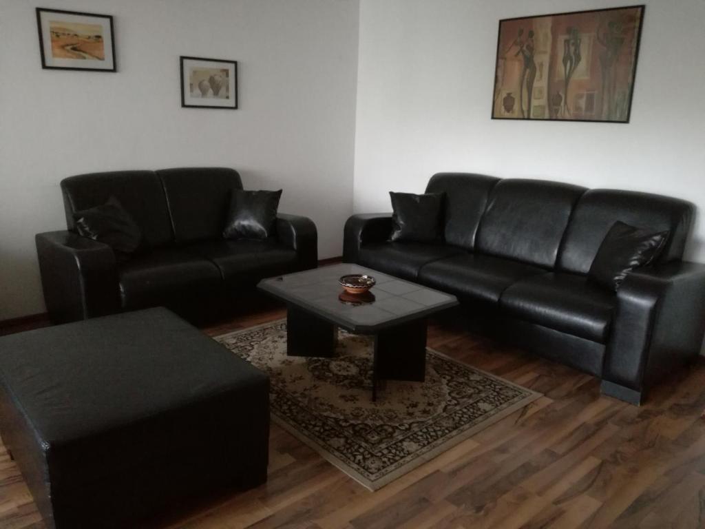 a living room with a black leather couch and a table at Apartment City-VIC in Vienna