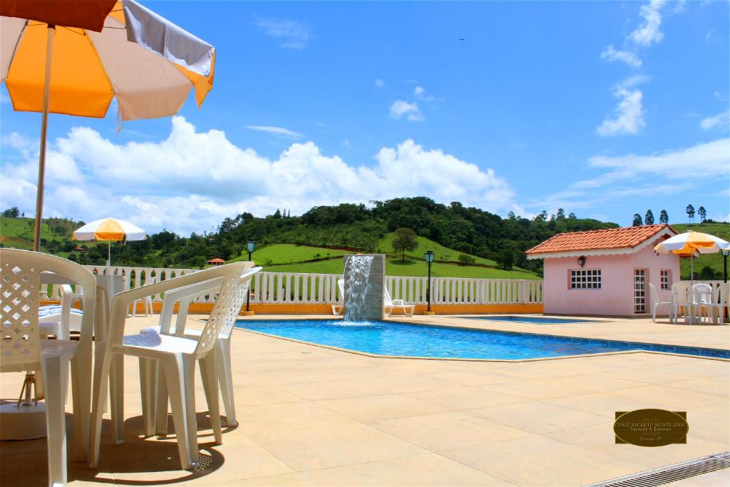 a patio with an umbrella and a swimming pool at Chalé Recanto Monte Sinai in Piracaia