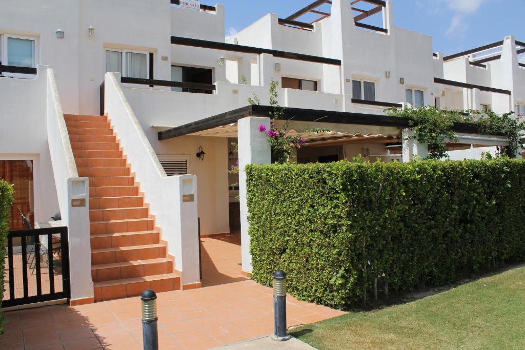 El RomeroにあるApartamento en Murcia Golf Resortの階段と緑の垣根のある白い家