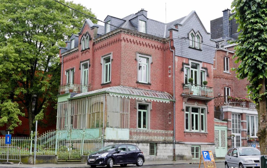 um carro preto estacionado em frente a um edifício de tijolos em B&B Villa le Vert-Bois em Spa