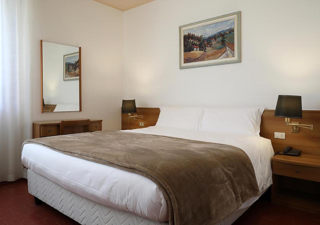 a bedroom with a large white bed and two lamps at Hotel Dante in Ponte nellʼAlpi